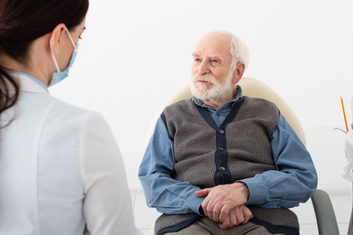 senior patient in dental chair taking consultation from doctor in medical mask,stock image